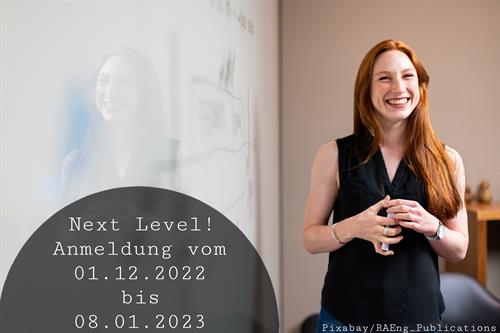 Frau vor einer Tafel mit Info zur Anmeldung für Next Level. 